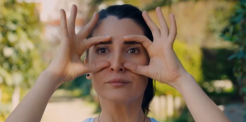 a lady performing owl facial exercise by stretching the eyelids using fingers 